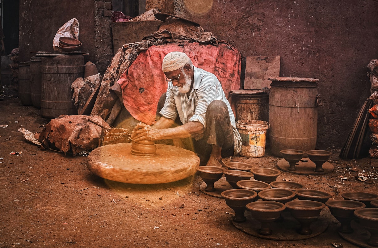 man in white dress shirt and brown pants holding brown clay pot