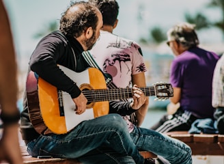 man in black long sleeve shirt playing acoustic guitar