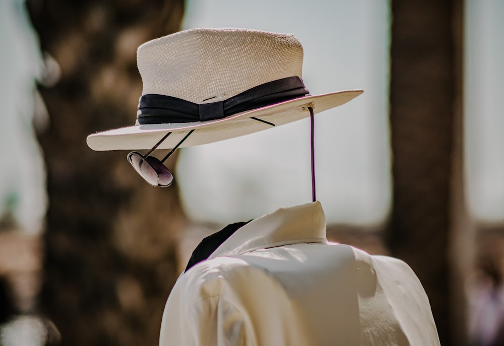 pessoa vestindo camisa social branca e chapéu fedora marrom