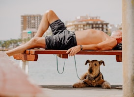 en man i svarta shorts som chillar på en bänk med sin hund
