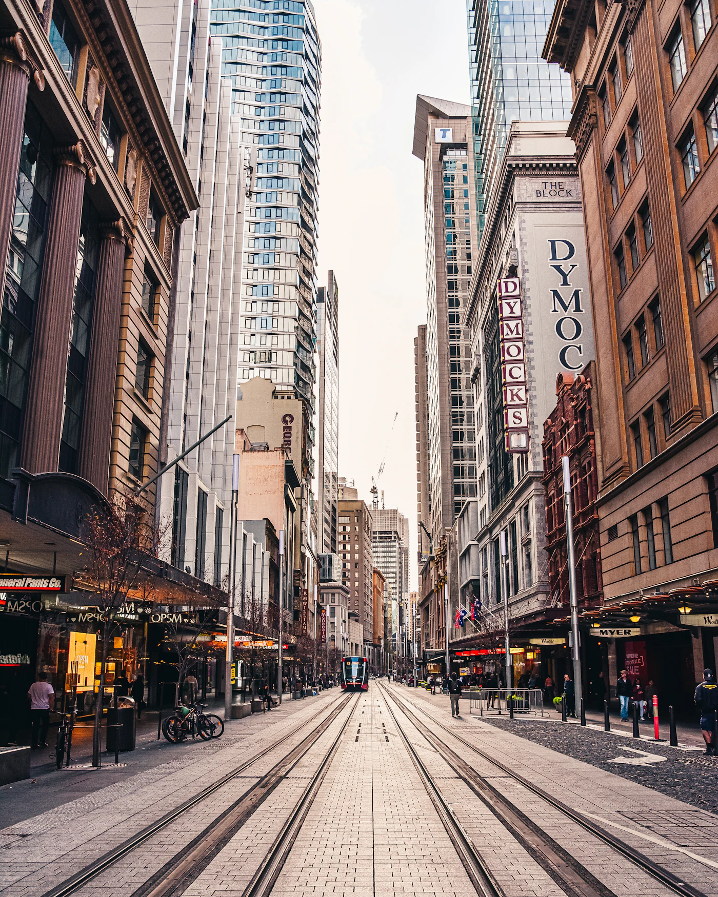 People walking along George Street between office towers in the Sydney CBD