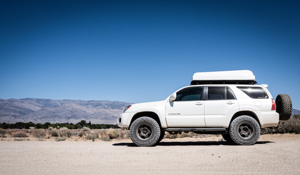 Camioneta pickup blanca de cabina doble en arena marrón bajo cielo azul durante el día