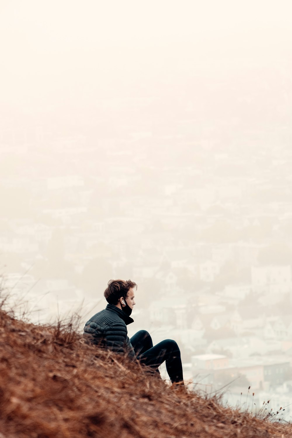 man in blue jacket sitting on brown grass during daytime