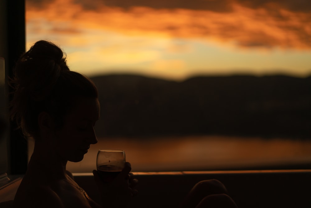woman drinking beer on clear drinking glass during sunset