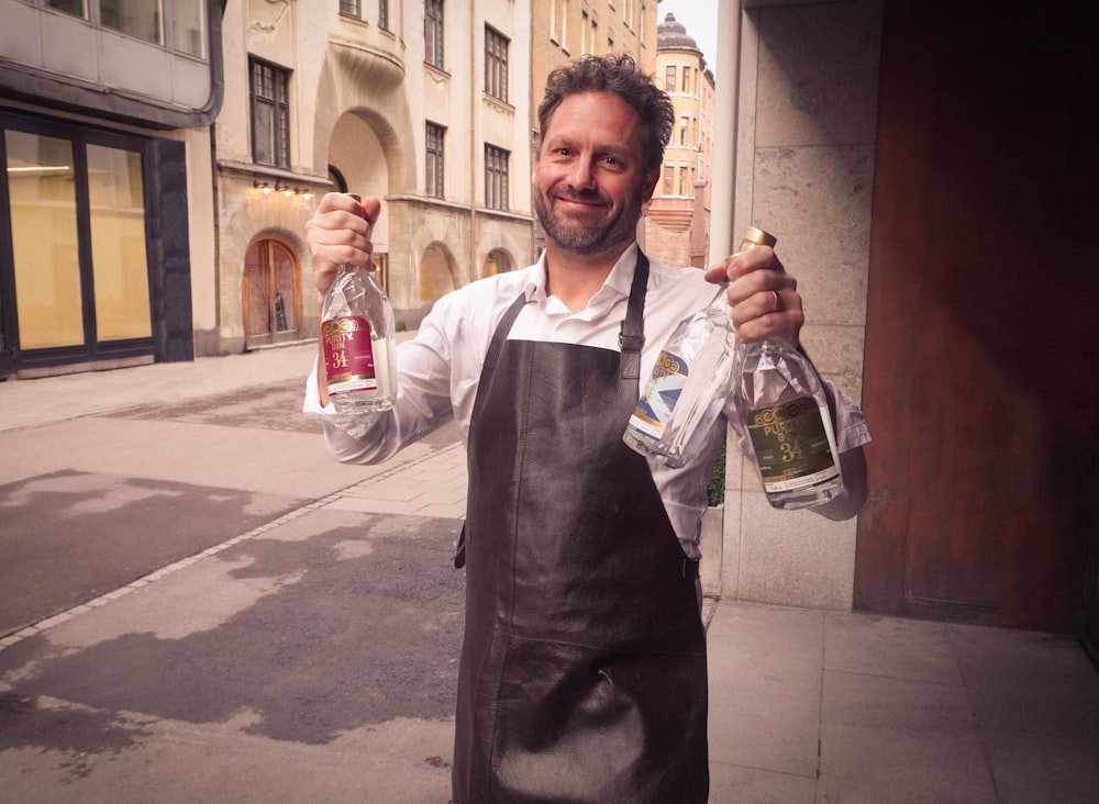 man in white dress shirt holding glass bottle