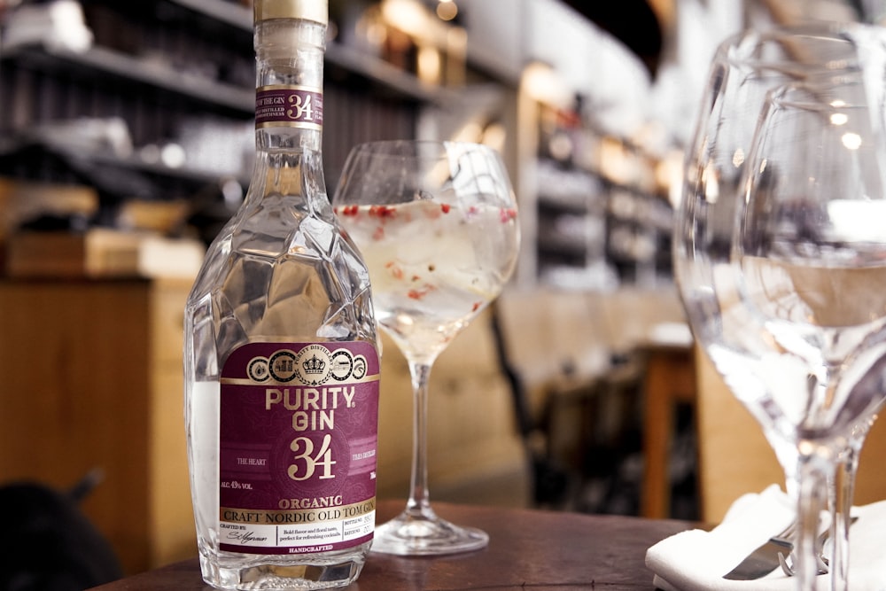 UNKs london garrafa de gin seco ao lado de taça de vinho transparente na mesa de madeira marrom