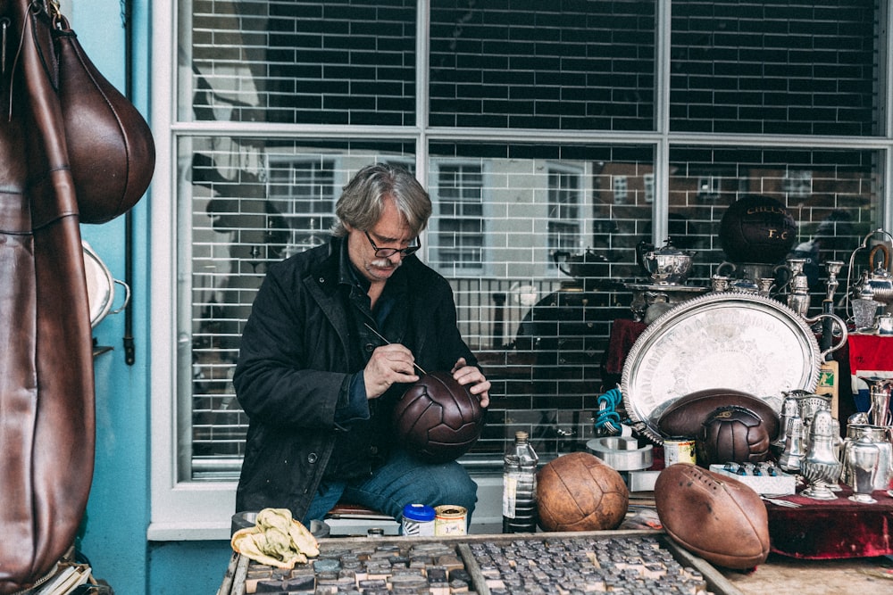 man in black jacket sitting on brown wooden table