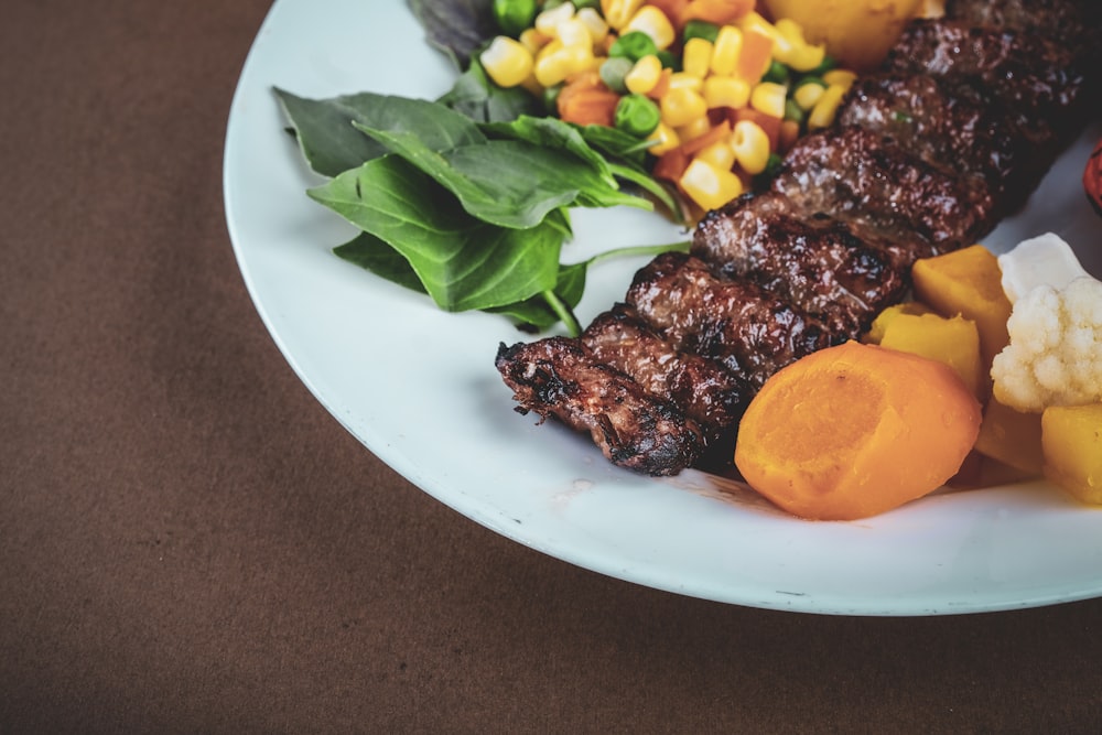 Carne a la brasa con verdura verde sobre plato de cerámica blanca