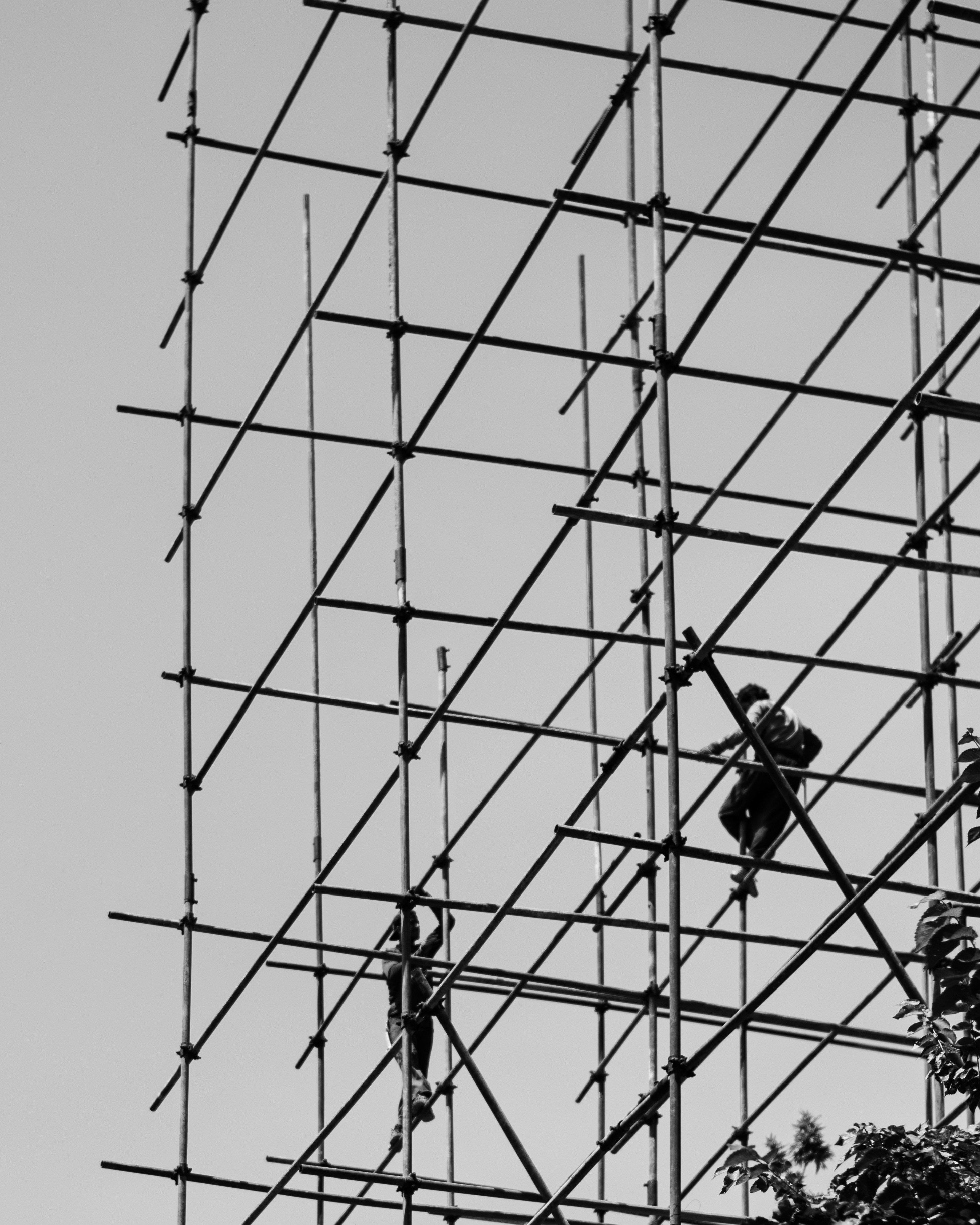 Steel framework of a specialty construction project with workers and scaffolding against a clear sky