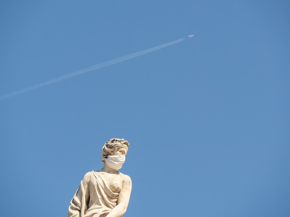 낮 동안 푸른 하늘 아래 흰 셔츠 동상을 입은 남자