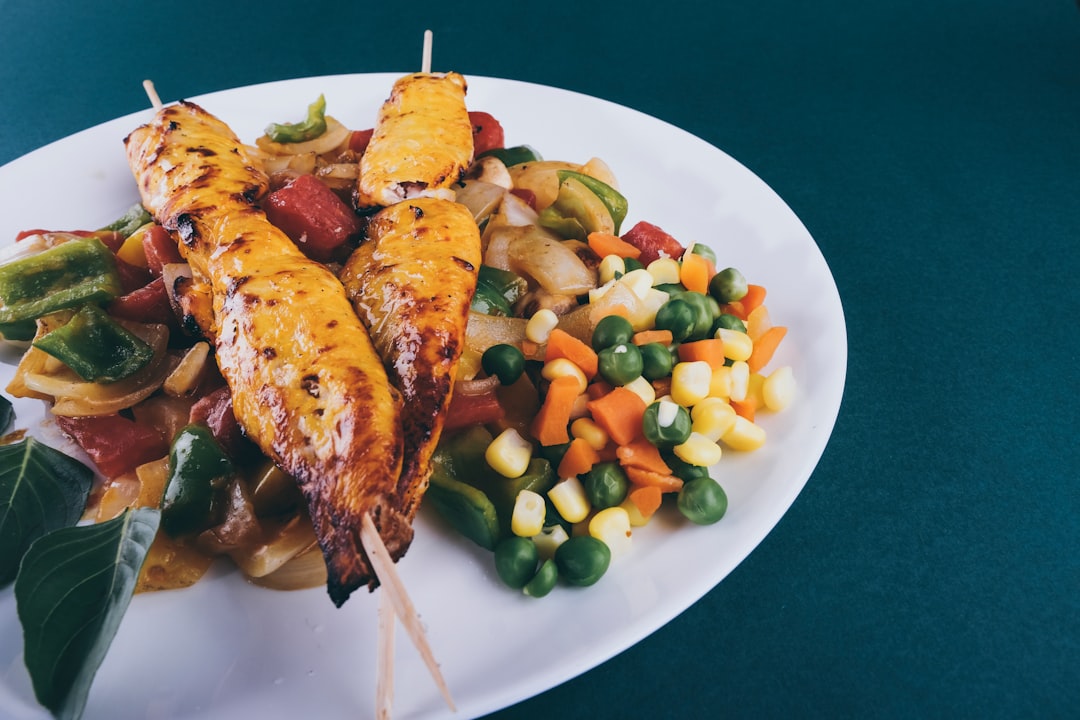 grilled meat with green peas and carrots on white ceramic plate