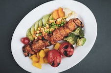 balanced meal of grilled meat with sliced lemon and sliced tomatoes on white ceramic plate