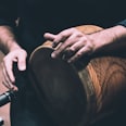 person in black shirt holding brown wooden drum