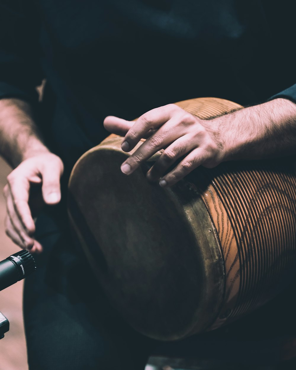 person in black shirt holding brown wooden drum