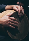 person in black shirt holding round brown wooden table