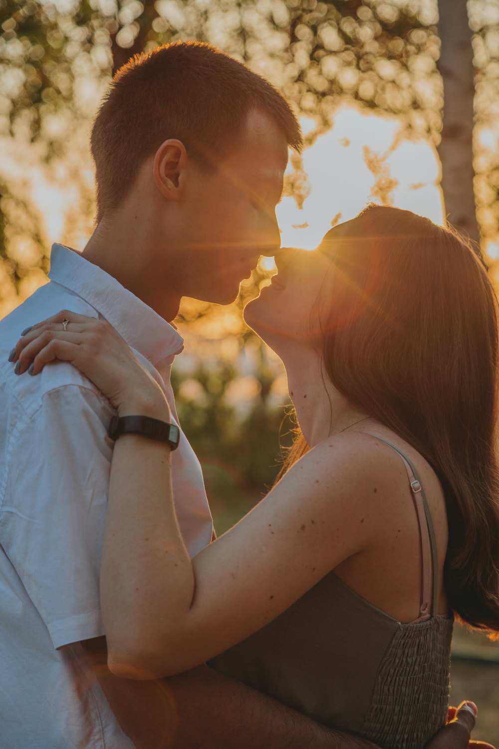 homem no terno branco beijando a mulher no vestido branco sem mangas durante o pôr do sol