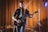 man in black suit playing guitar