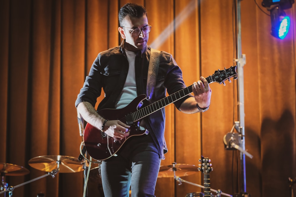 homem no terno preto que joga guitarra