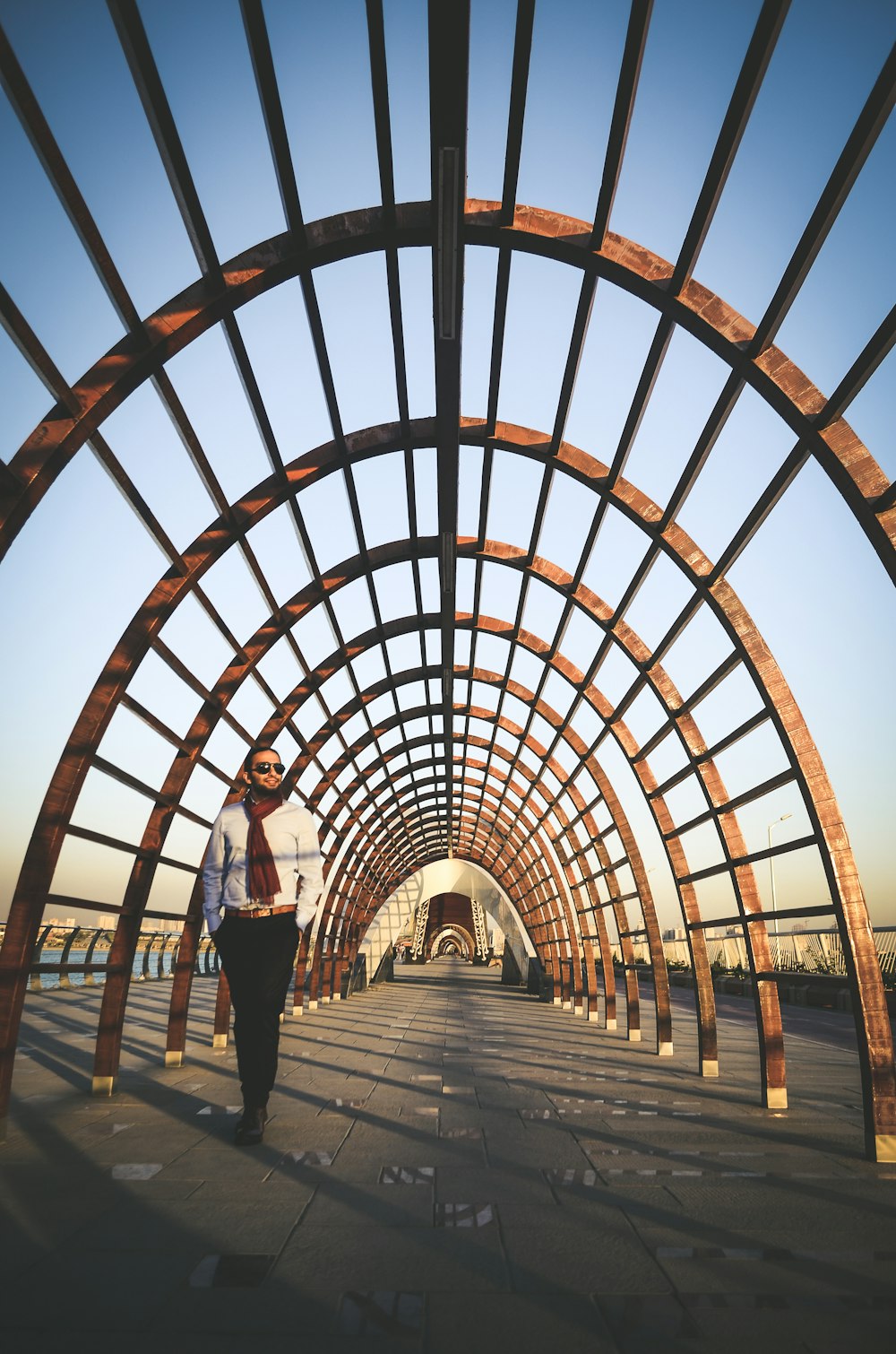 man and woman standing on brown wooden pathway under brown metal arch