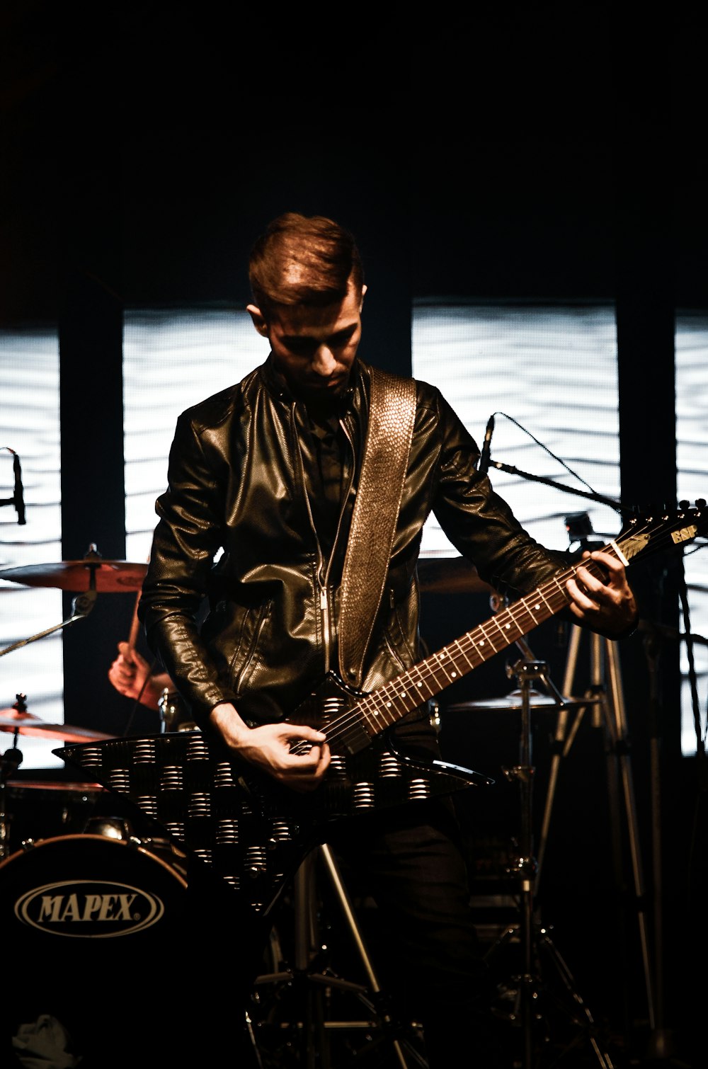 hombre con chaqueta de cuero negro tocando la guitarra
