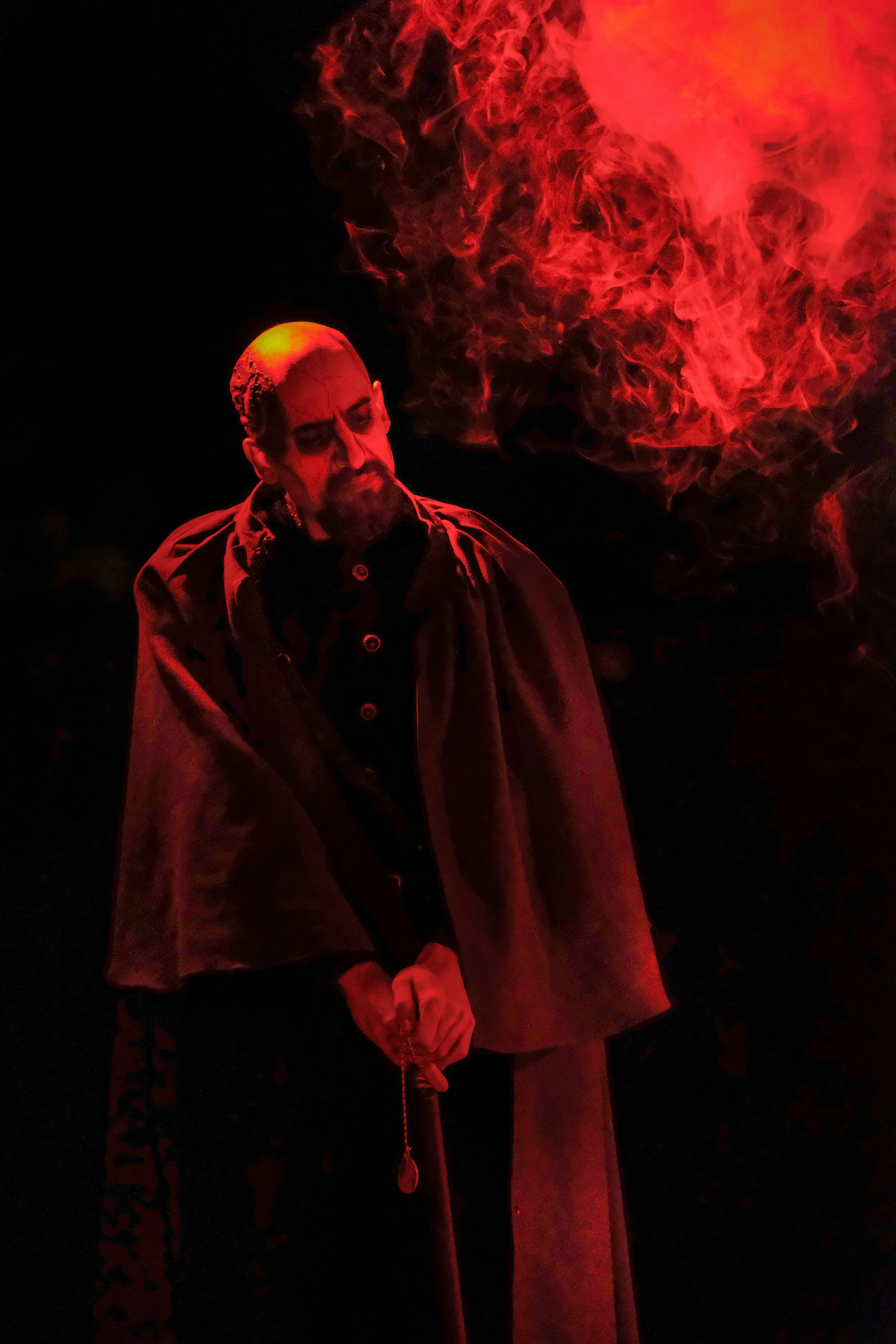 man in black coat standing near red fire