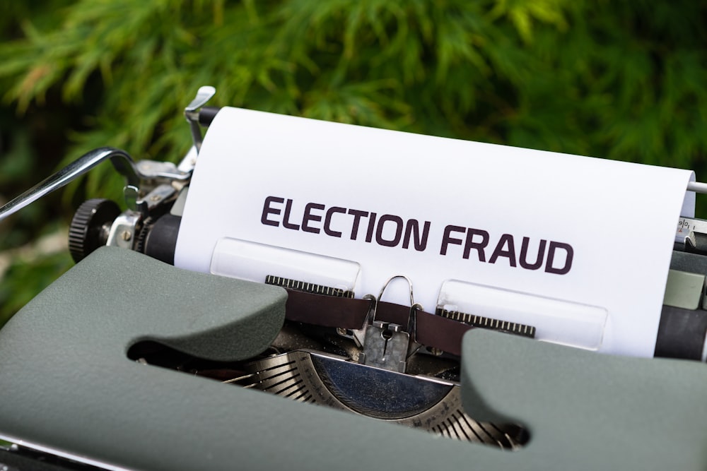 a close up of a typewriter with a paper that reads election fraud