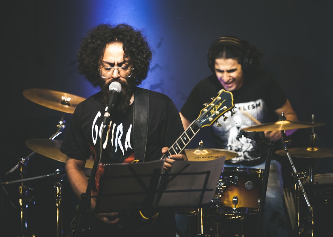 man in black and white crew neck t-shirt playing guitar