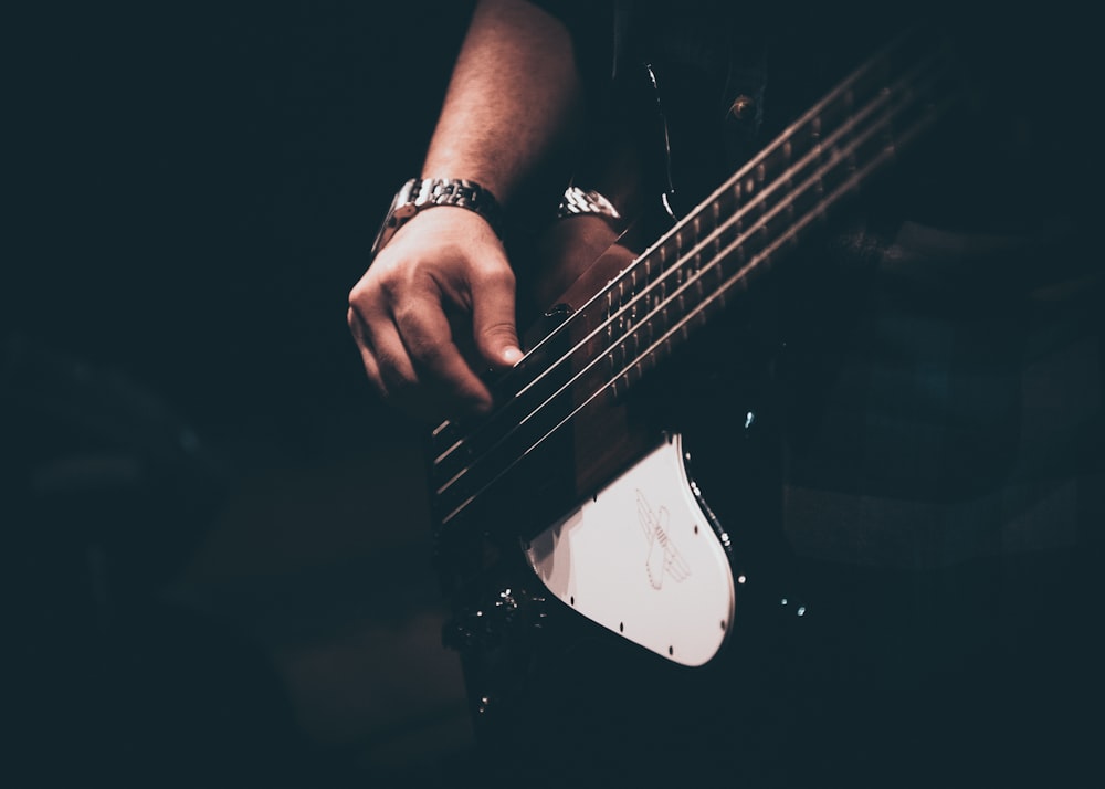 person playing white and black electric guitar