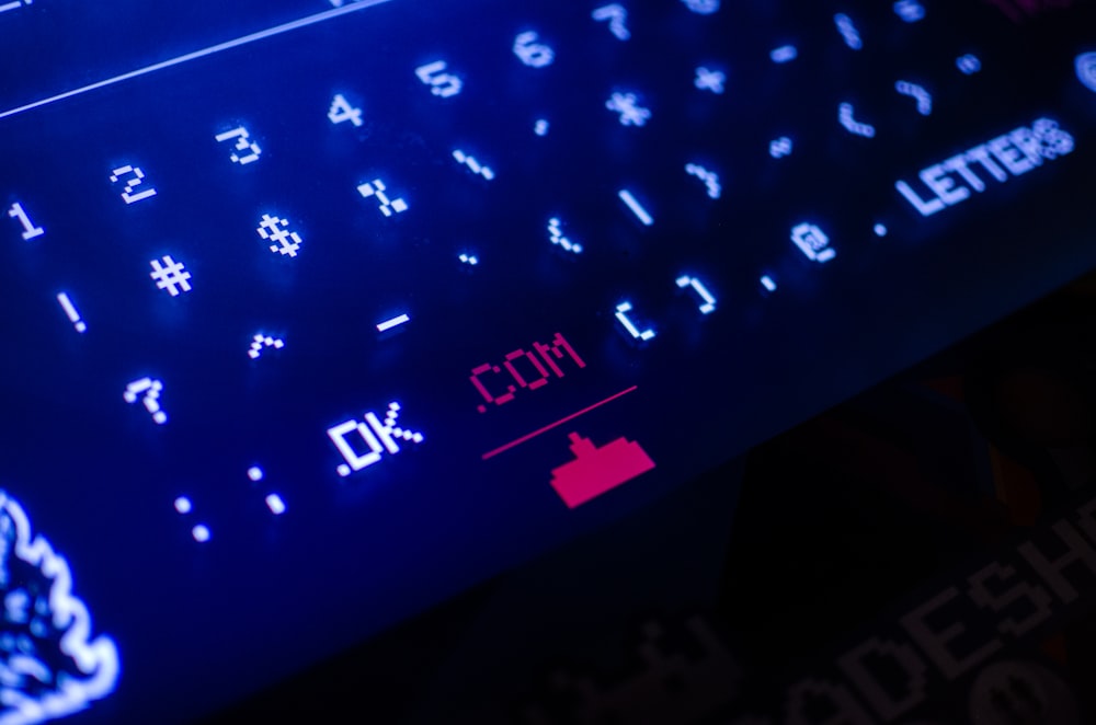 لوحة مفاتيح الكمبيوتر باللونين الأسود والأزرق تسلط الضوء على .com وهو من نطاقات المستوى الأعلى.
