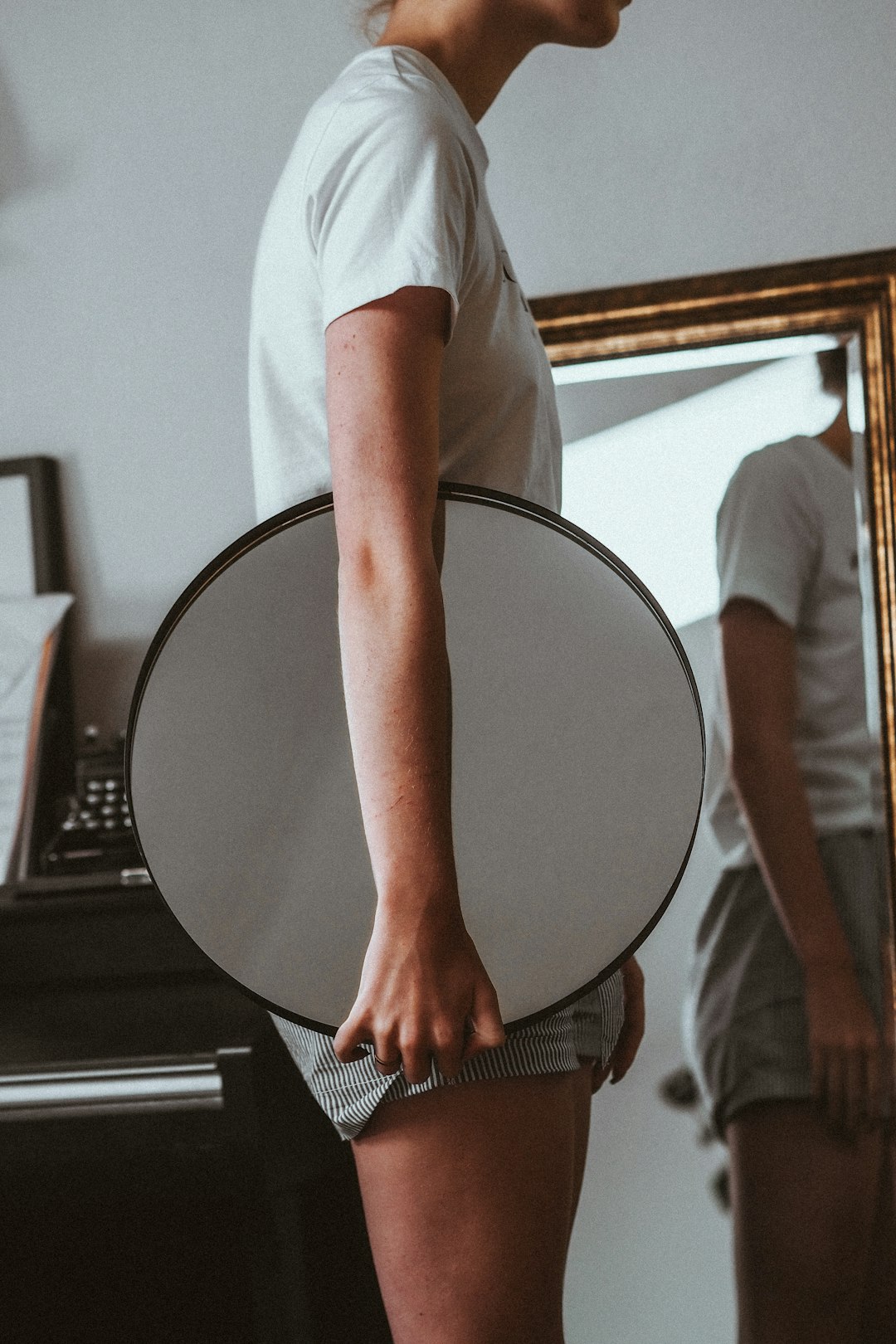 man in white t-shirt holding round mirror