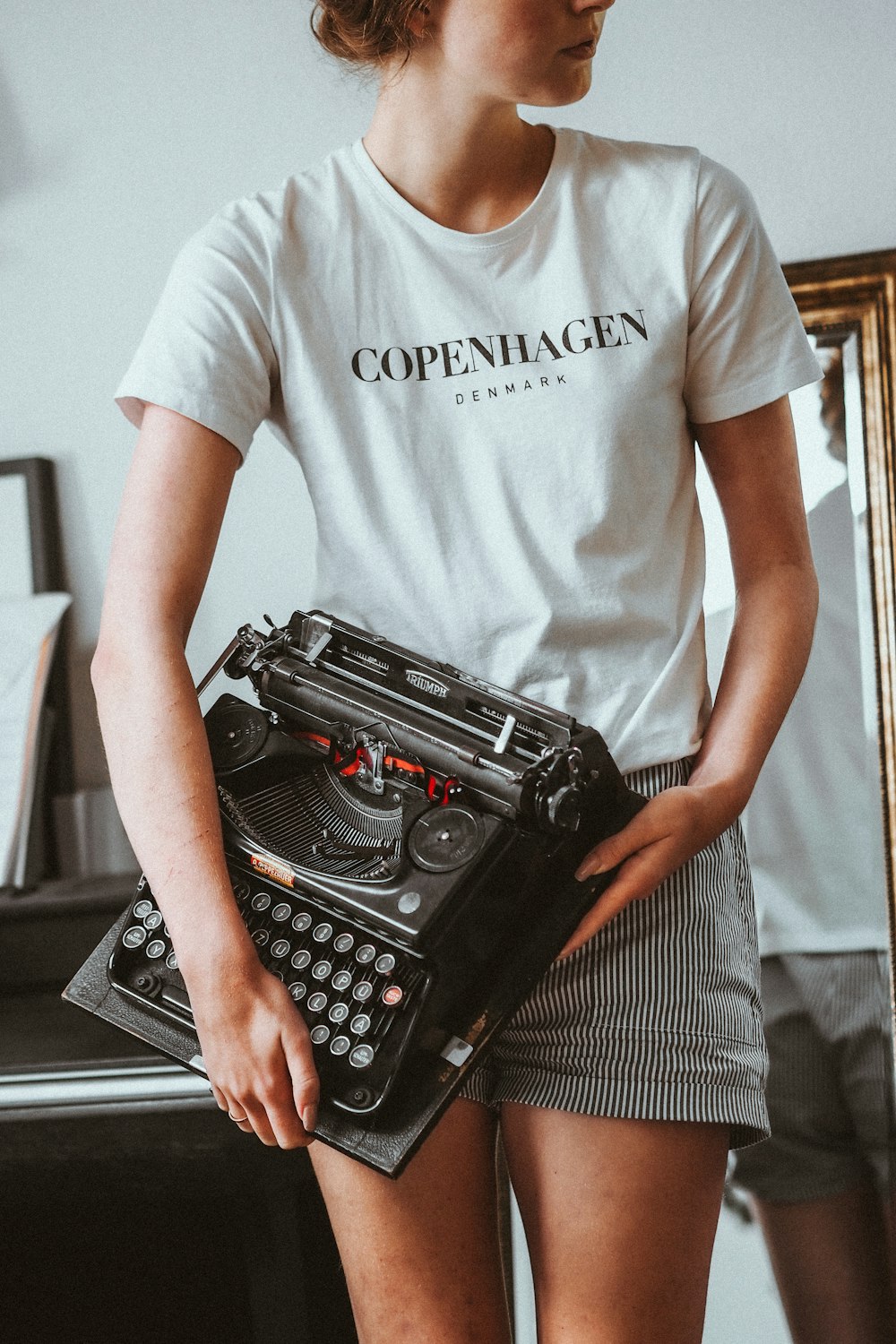 man in white crew neck t-shirt holding black typewriter