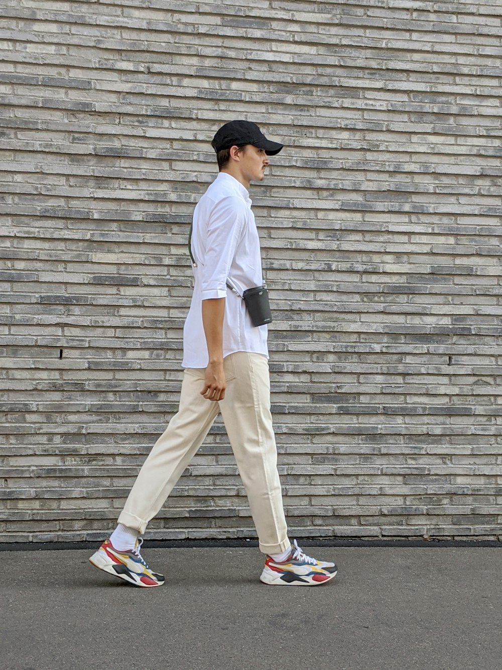 man in white t-shirt and beige pants standing on gray concrete floor