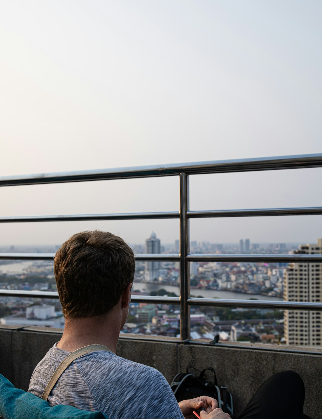 man in white shirt looking at the city during daytime