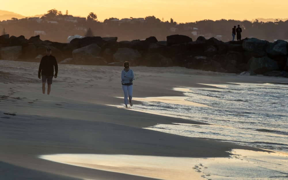 man and woman walking on white sand during daytime