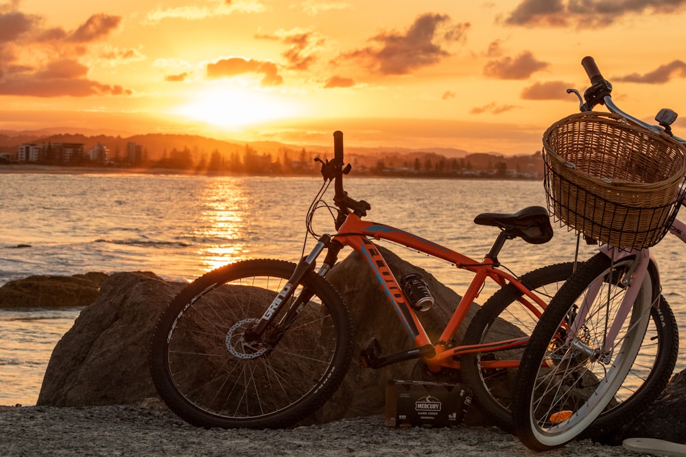 red and black mountain bike near body of water during sunset