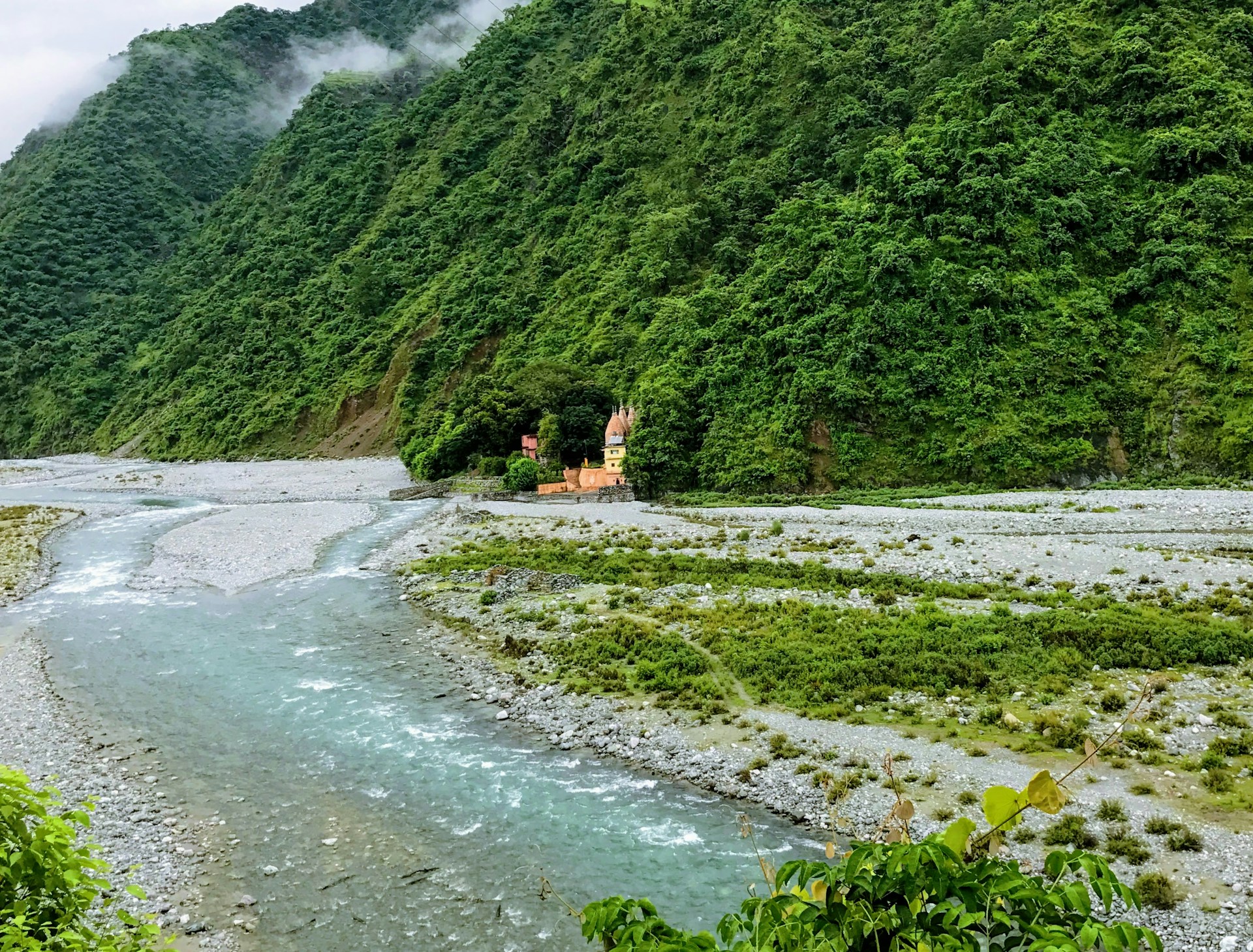 A serene view of the Ambagahakotuwa Temple surrounded by lush greenery and mountains.