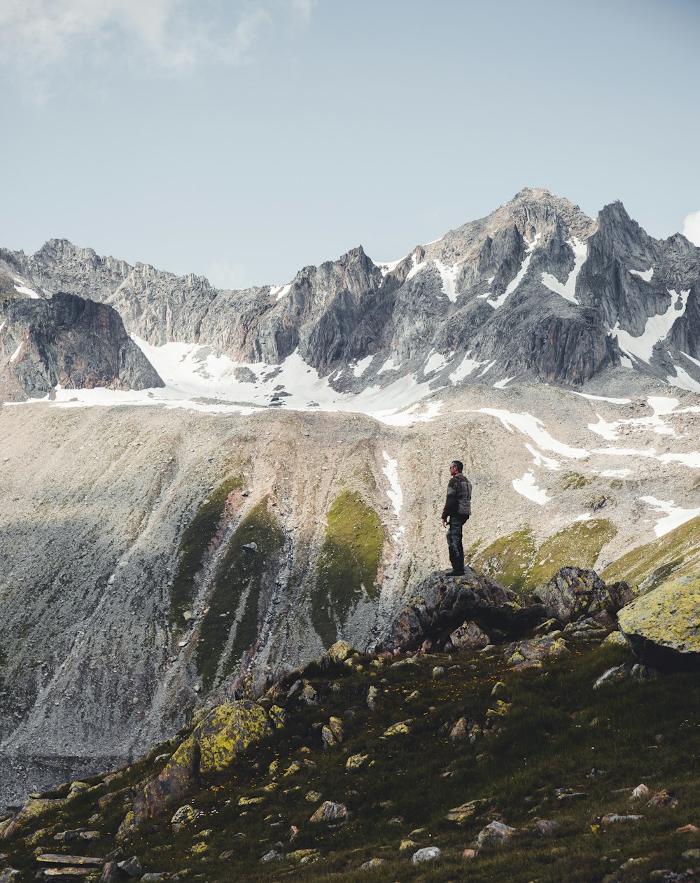 person standing on green grass near snow covered mountain during daytime