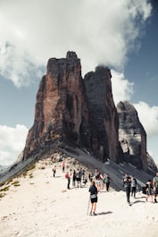 people walking on white sand near brown rock formation during daytime