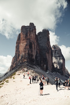people walking on white sand near brown rock formation during daytime
