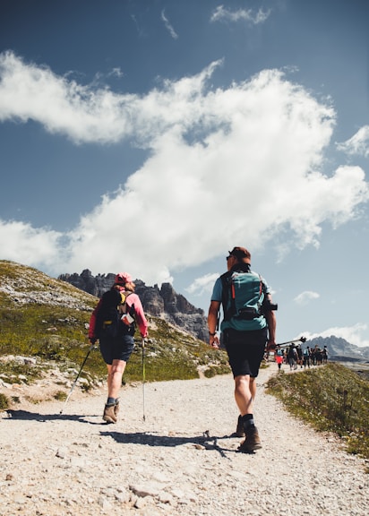 man in green shirt and black shorts with hiking backpack walking on gray sand during daytime