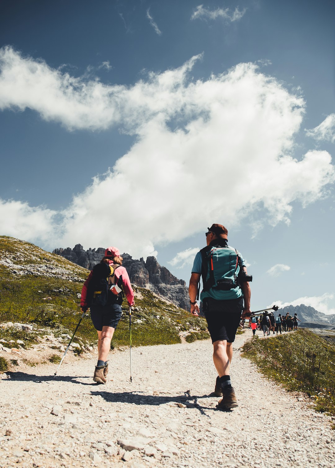 man in green shirt and black shorts with hiking backpack walking on gray sand during daytime