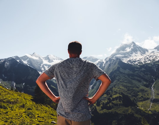 man in grey and black crew neck t-shirt standing on green grass field during daytime in Grossglockner Austria