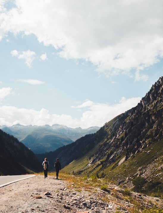 person walking on road near mountains during daytime