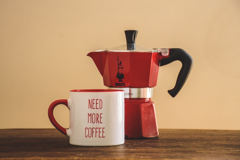 red and silver coffee maker beside white ceramic mug