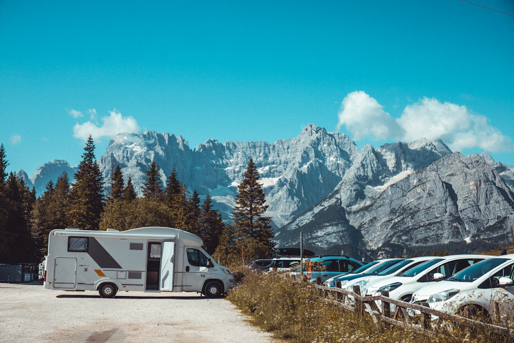 A motorhome parked beneath jagged mountain peaks