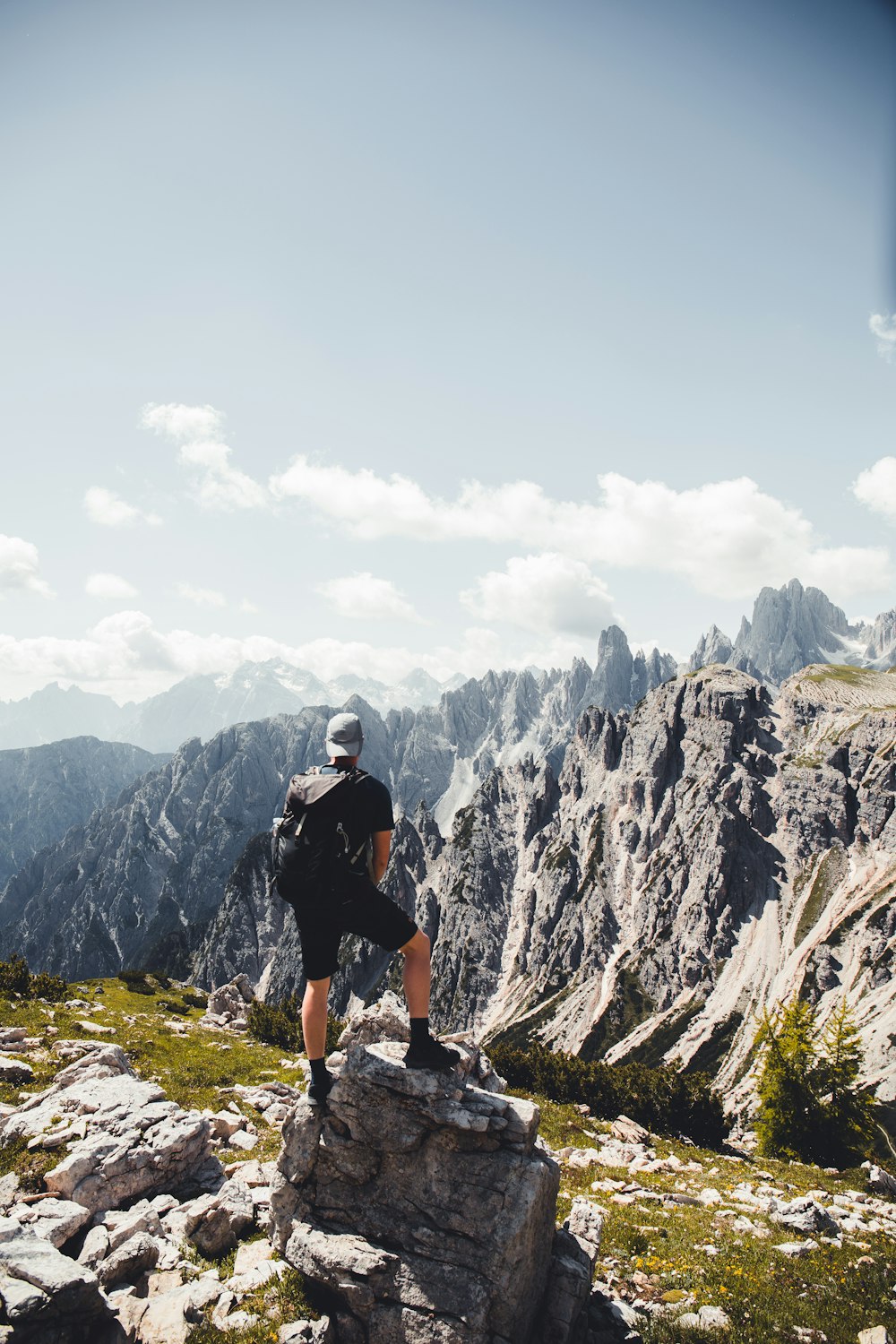 man in black t-shirt and black shorts standing on rocky mountain during daytime