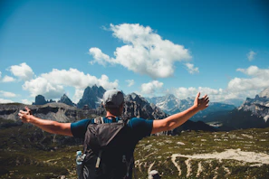 A person stretching arms wide at sunrise on a mountain trail in Swiss Alps