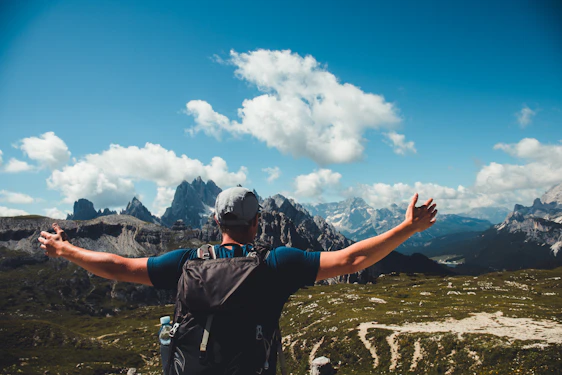 A joyful traveler standing on a mountain peak at sunrise, arms wide open embracing the adventure.