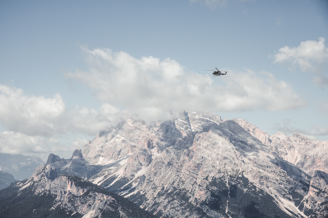 black helicopter flying over snow covered mountain during daytime