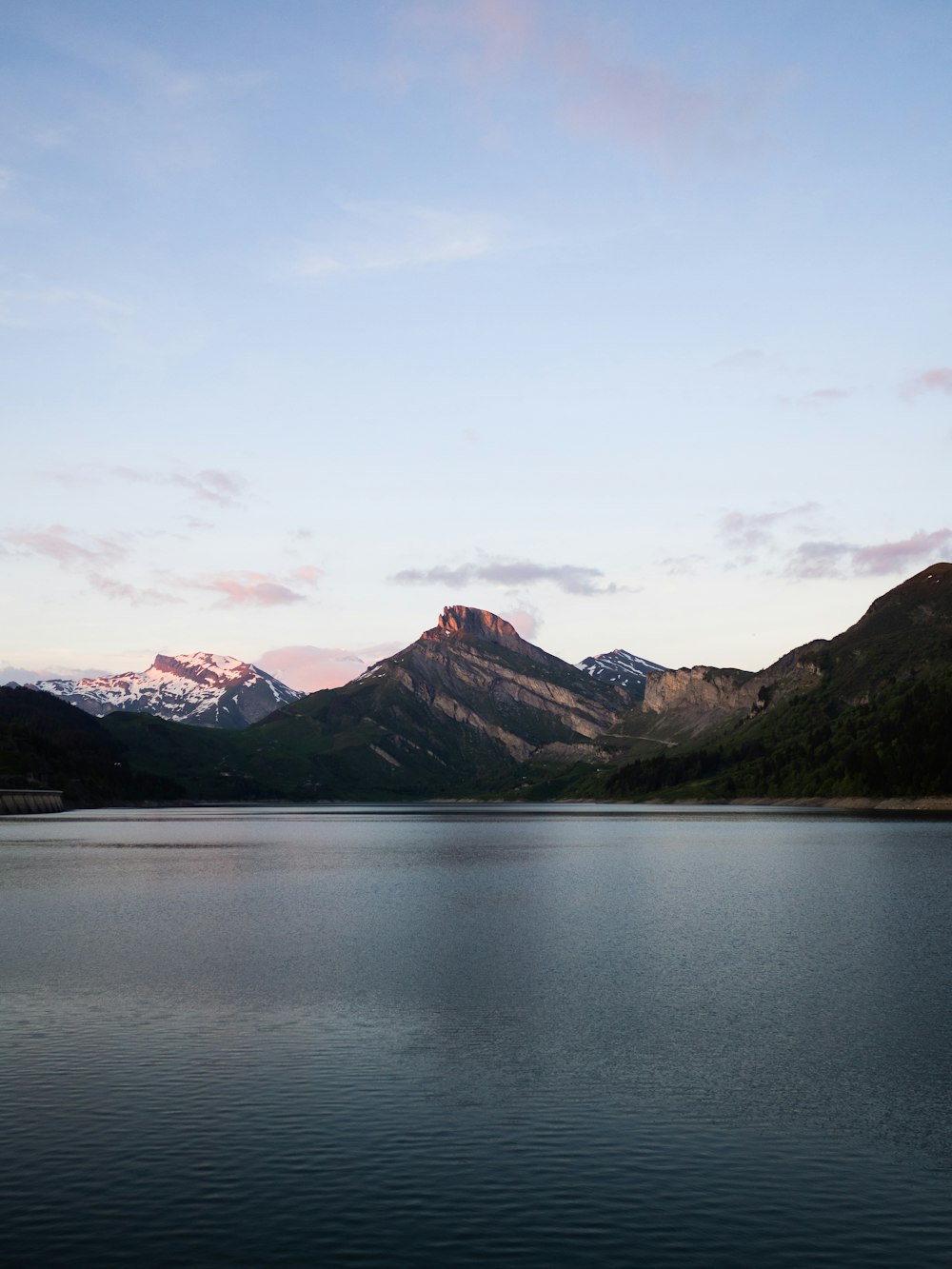 lake near mountain under white sky during daytime